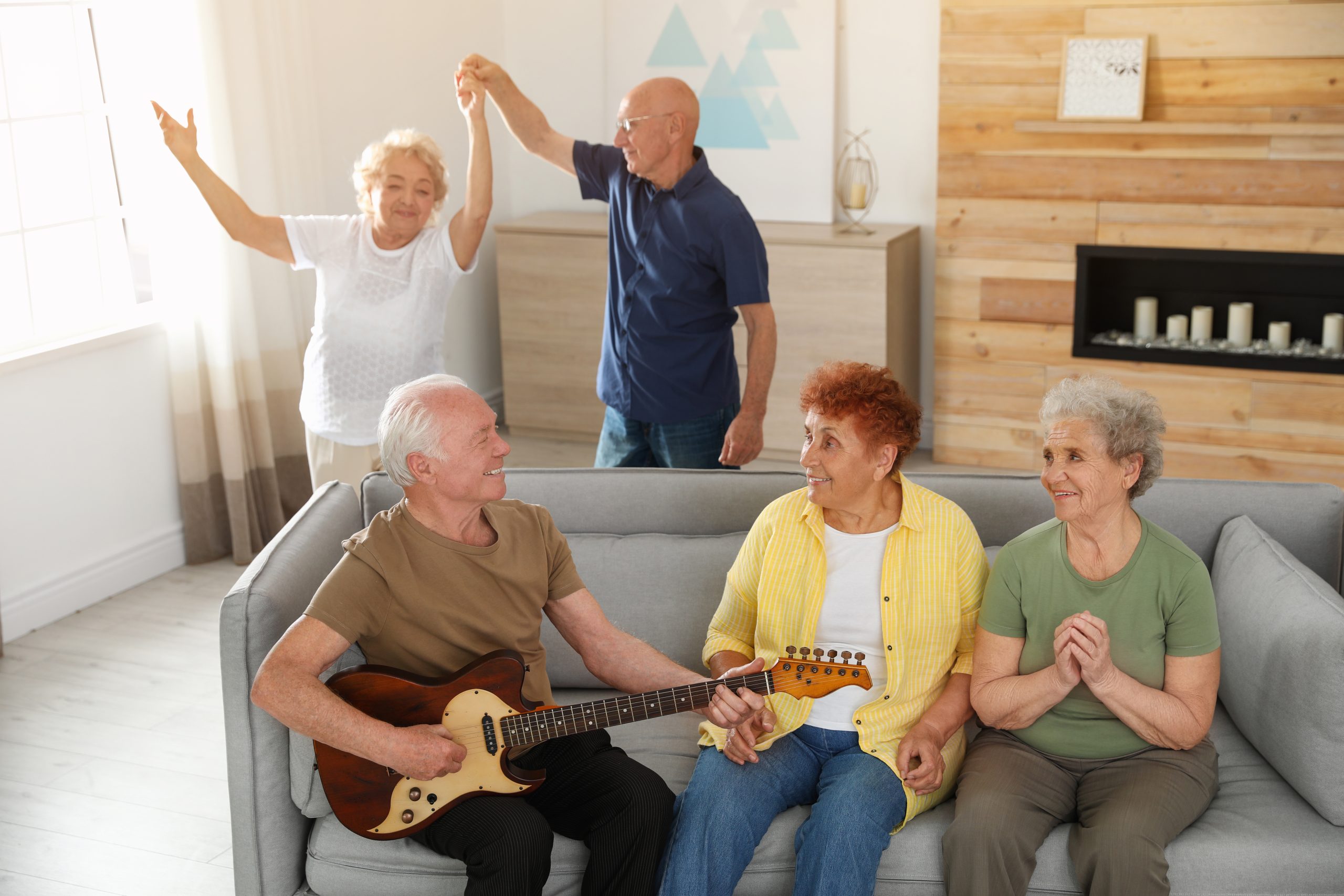 A group of older adults enjoy music together in a living room