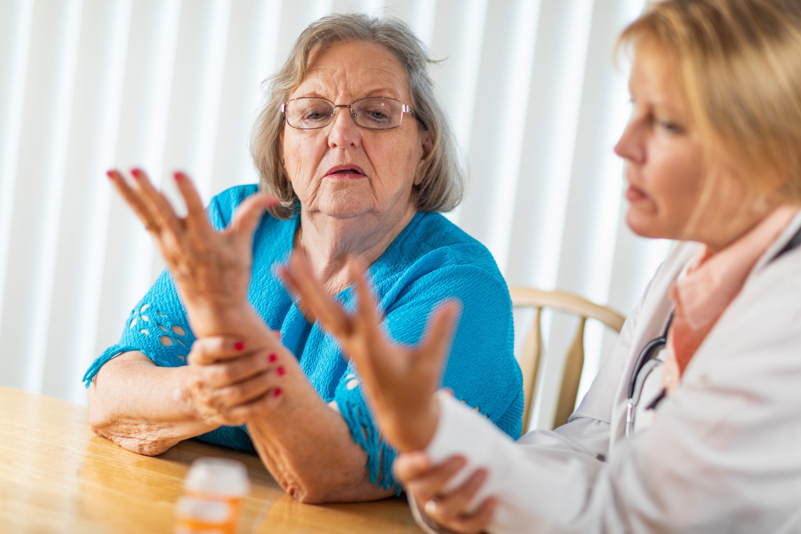Female Doctor Talking with Senior Adult Woman About Hand Therapy.